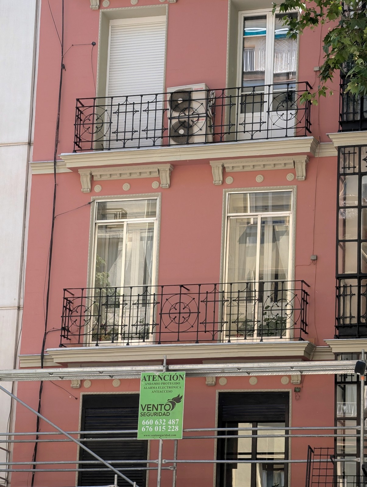Detalle de balcones de hierro forjado y cornisa con dentículos en edificio protegido de Madrid